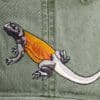 A lizard is embroidered on the side of a hat.
