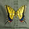 A yellow butterfly is on the back of a green hat.