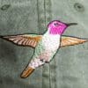 A hummingbird embroidered on the back of a hat.