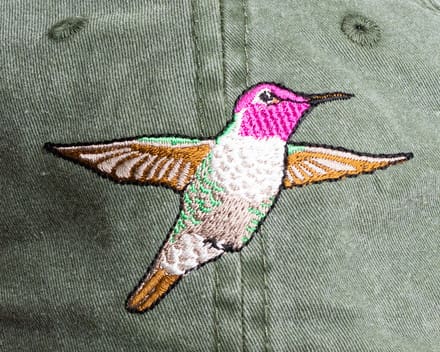 A hummingbird embroidered on the back of a hat.