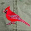 A red bird is embroidered on the back of an olive green hat.