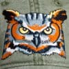 A close up of an owl patch on the hat