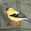 A yellow bird is sitting on the branch of a tree.
