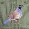 A bird is embroidered on the back of a green jacket.