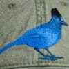 A blue bird is embroidered on the side of a hat.