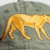 A close up of the back of a hat with an embroidered lion.