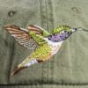 A hummingbird patch is shown on the back of a hat.