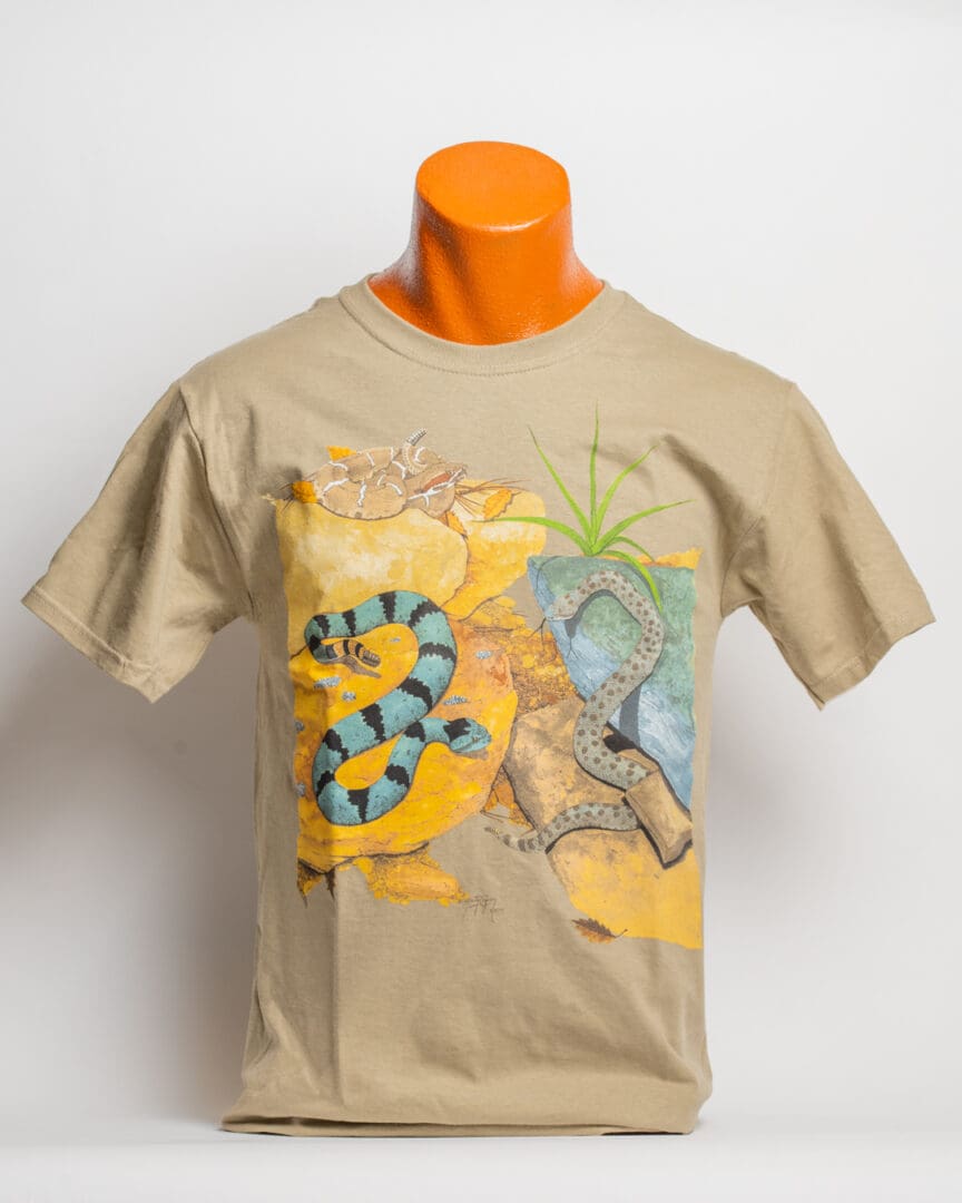 A tan t-shirt with an image of a snake and palm trees.