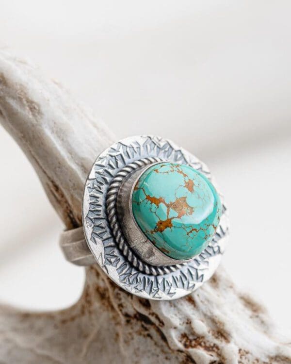 A silver ring with a turquoise stone on top of it.