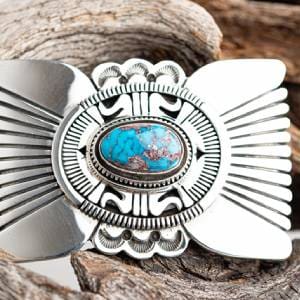 A silver belt buckle with a blue stone on it.