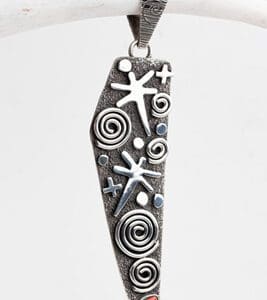 A silver pendant with swirls and stars on it.