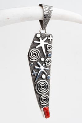 A silver pendant with swirls and stars on it.