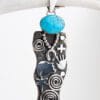 A silver pendant with a turquoise stone on it.