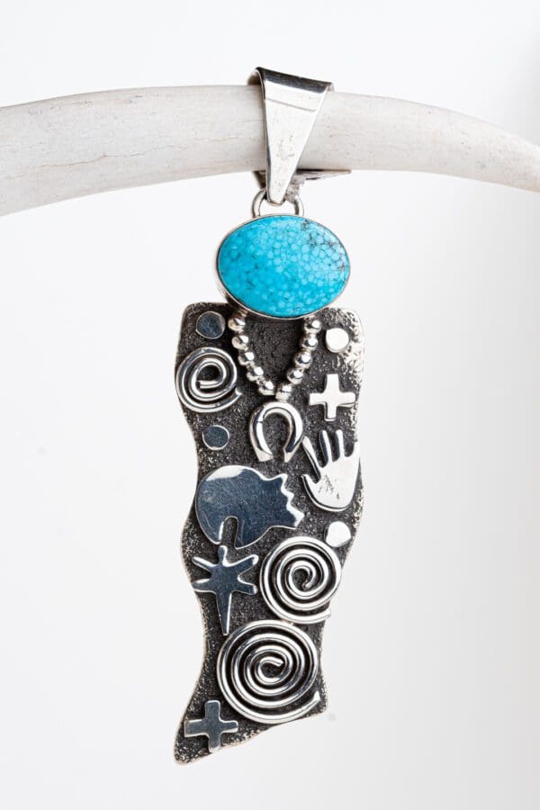 A silver pendant with a turquoise stone on it.