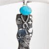 A silver necklace with a blue stone on it.
