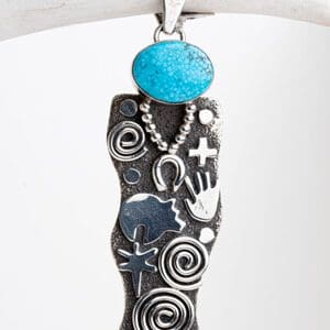 A silver necklace with a blue stone on it.