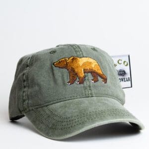 A green hat with an embroidered bear on it.