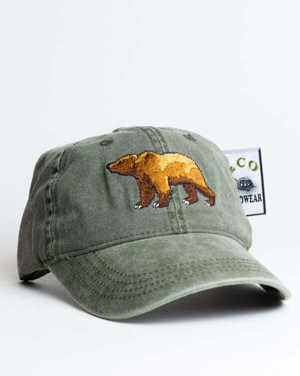 A green hat with an embroidered bear on it.
