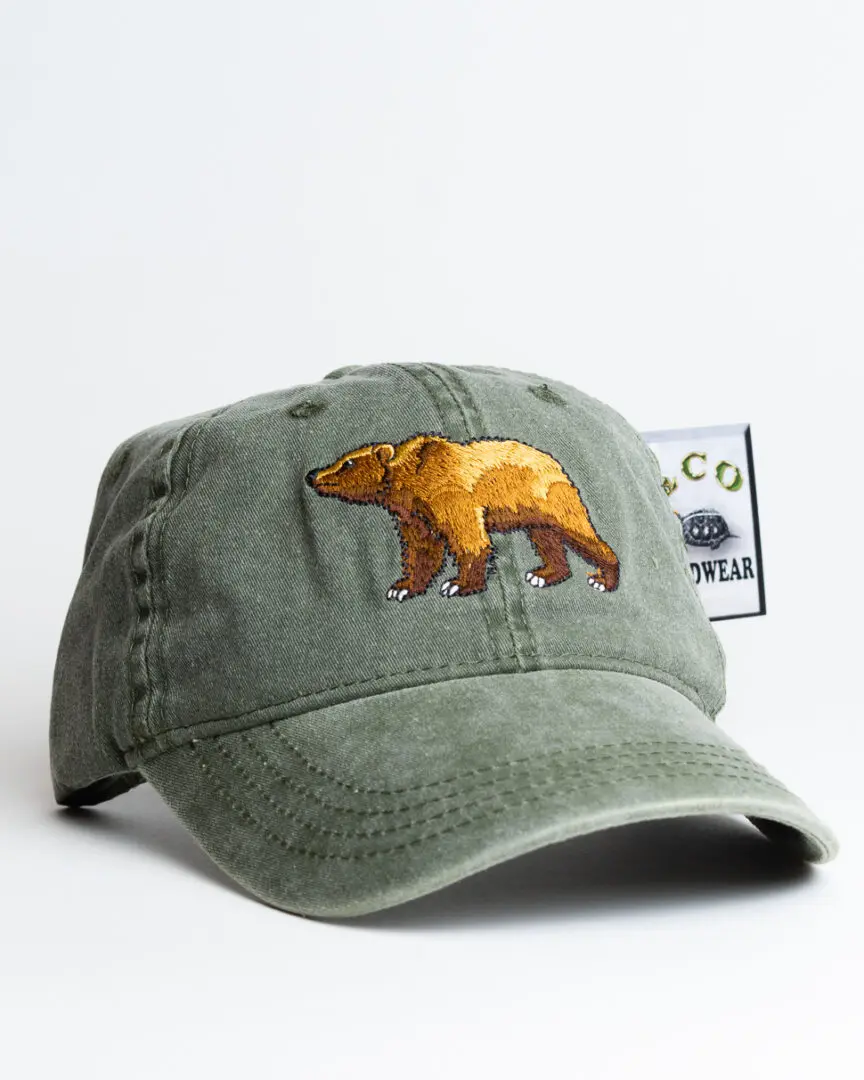 A green hat with an embroidered bear on it.