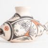 A white vase with black and orange designs on it.