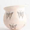 A white vase with butterflies on it.