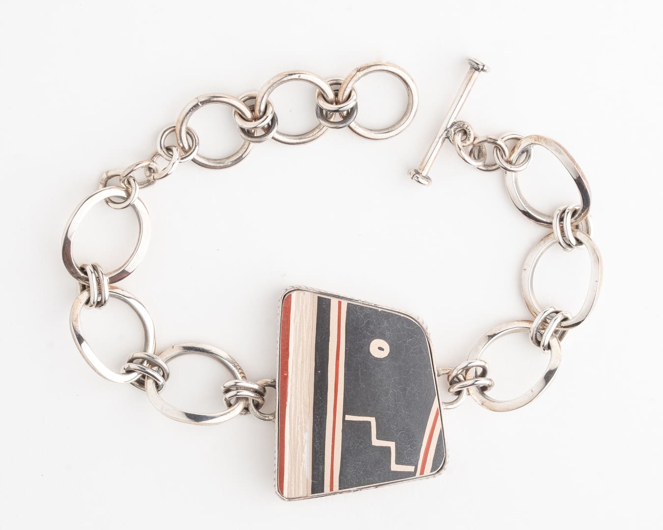A silver bracelet with a black and red striped design.