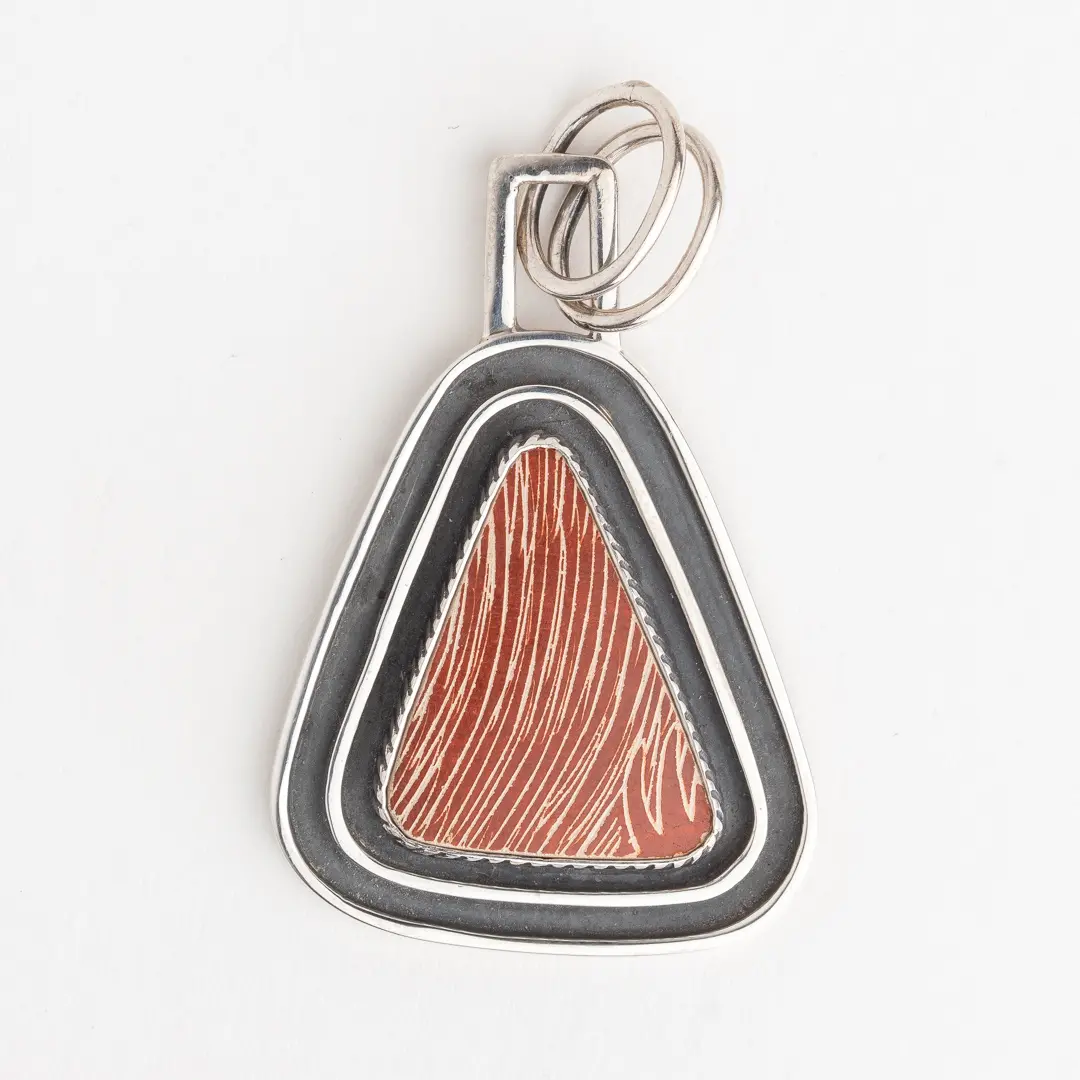 A triangle shaped pendant with a red and black design.