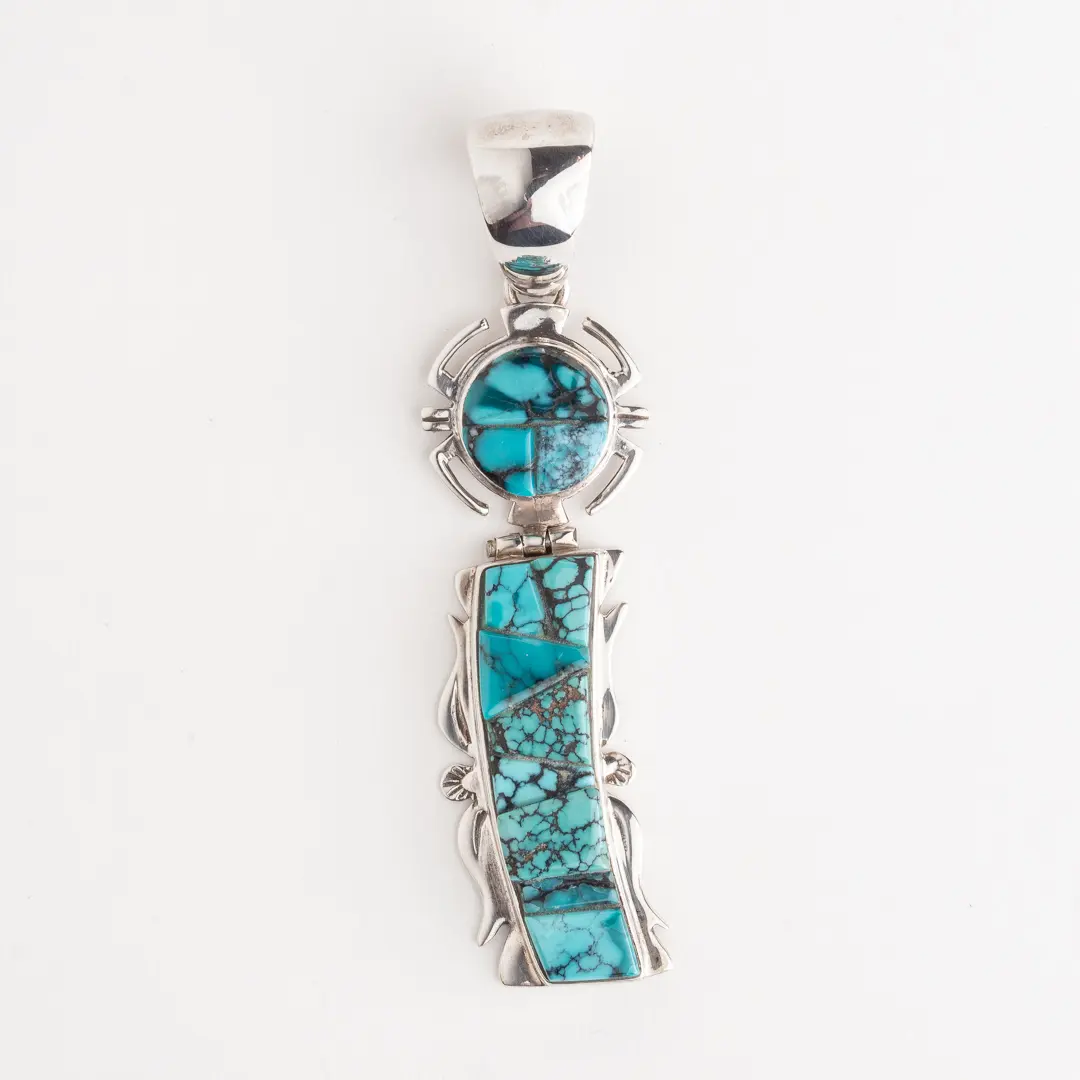 A silver pendant with turquoise and a stone.