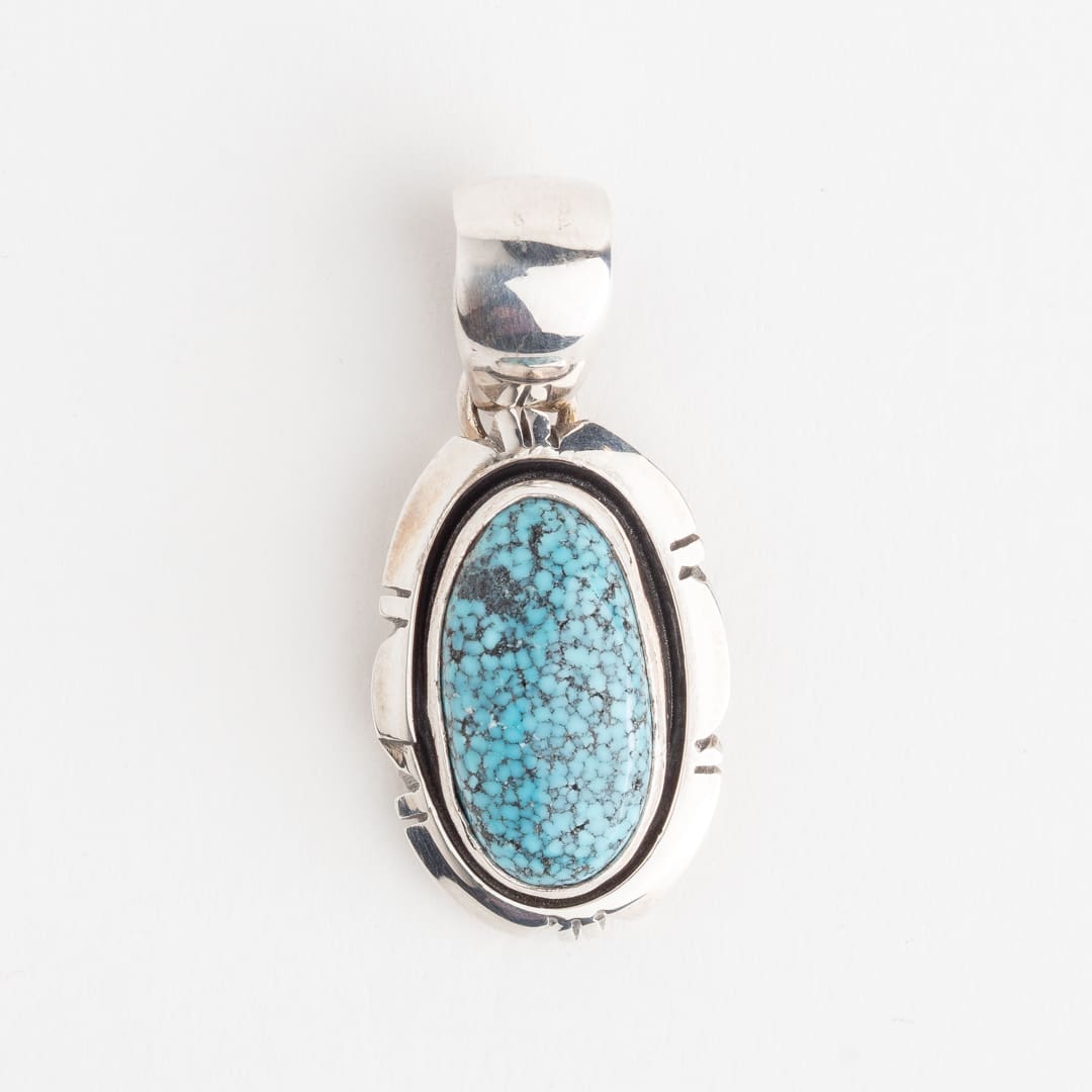 A silver pendant with a blue stone on it.