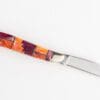 A knife with a colorful handle on top of it.