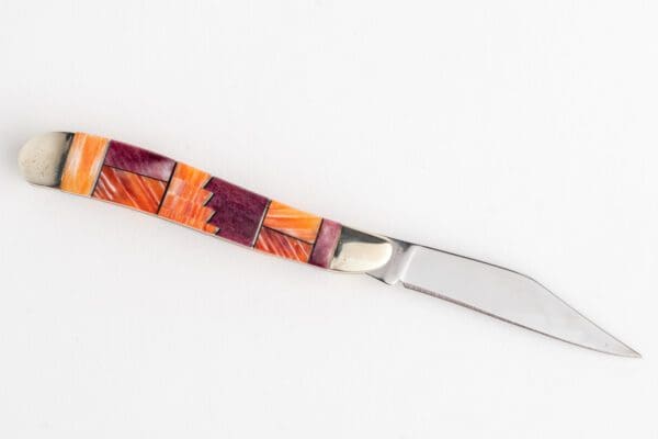 A knife with a colorful handle on top of it.