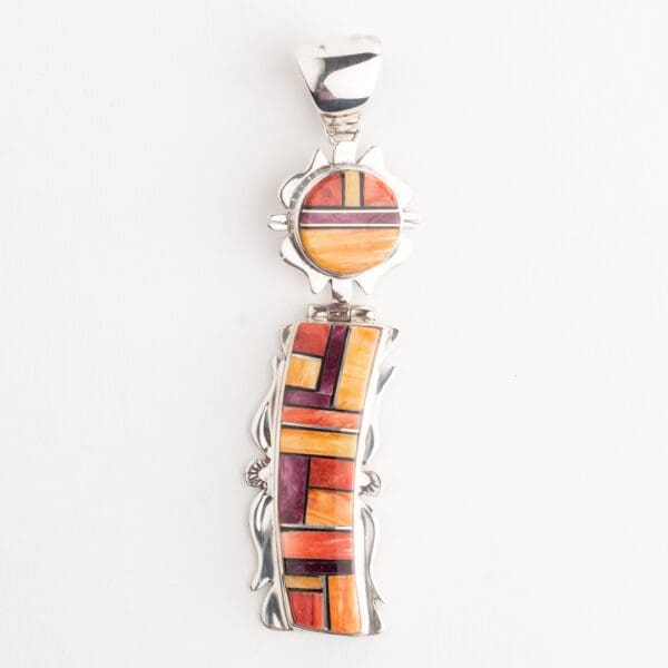 A silver pendant with a colorful design on it.