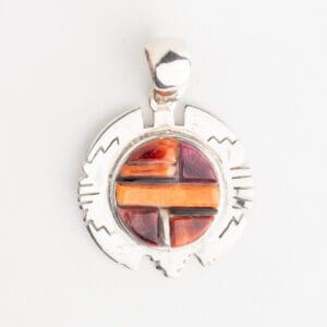 A silver pendant with an orange and purple design.