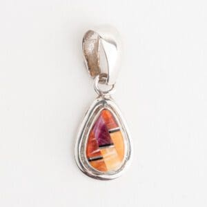 A silver pendant with an orange and purple stone.
