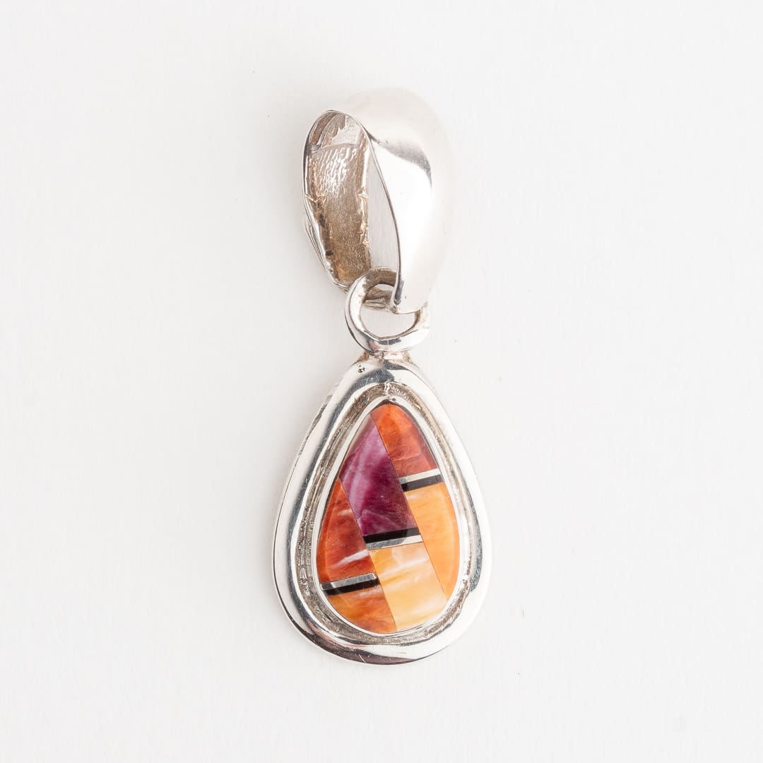 A silver pendant with an orange and purple stone.