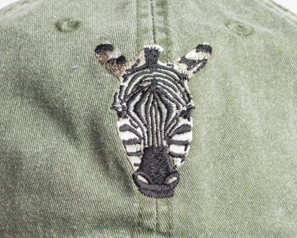 A zebra 's head is embroidered on the back of a hat.